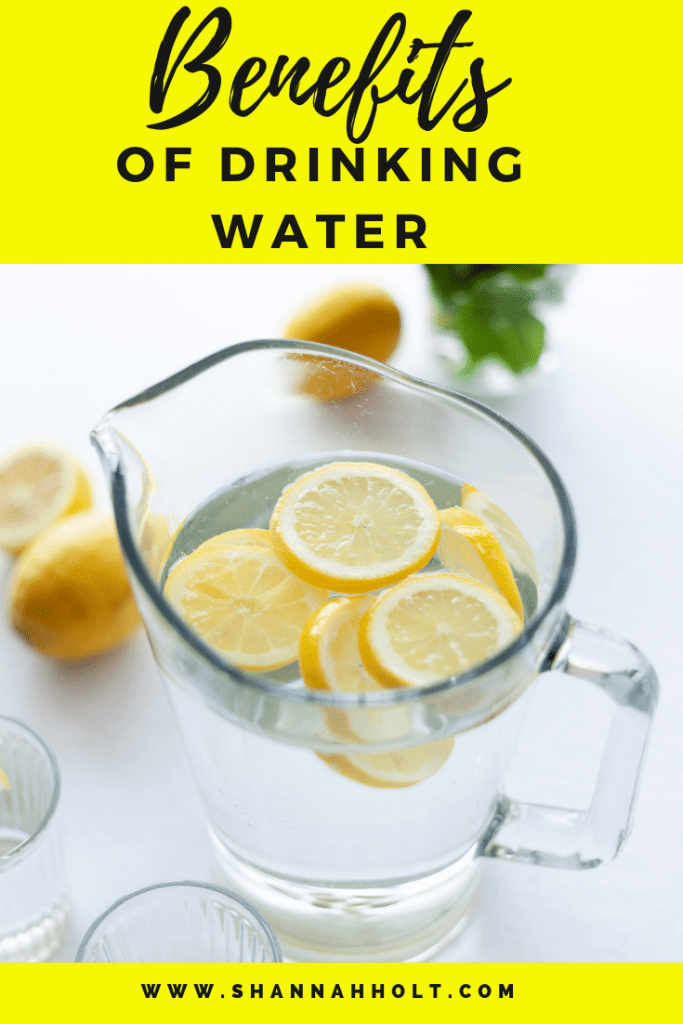 Glass pitcher with water and lemons with text Benefits of drinking water