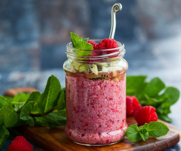 Raspberry chia pudding recipe in a glass jar with kiwi on top