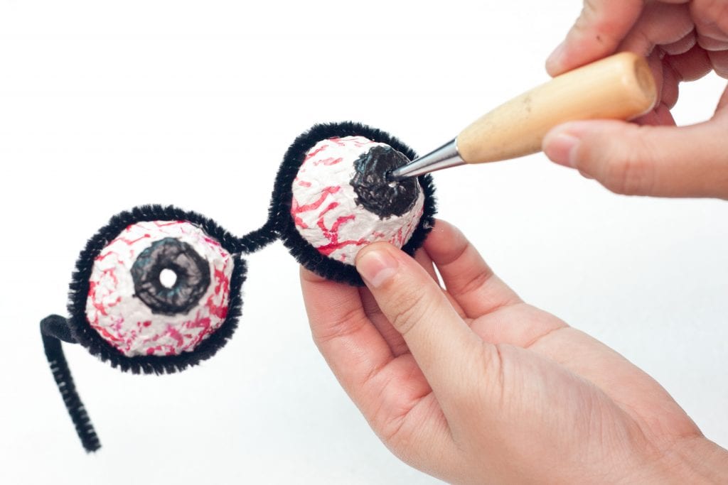 Halloween DIY Creepy Eyeball Glasses Step 12: Poke a hole in the middle of the pupil using a crafting awl hole tool. 