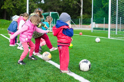 A group of 6-7 year olds playing soccer outside on a field. 