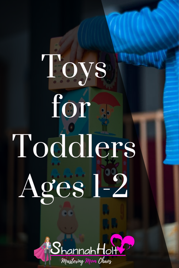 Toddler building a tower of big square blocks about the size of the child with text overlay Toys for toddlers ages 1-2