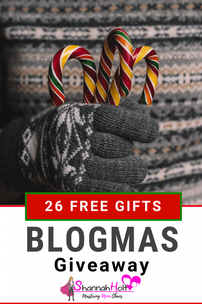 Woman in grey sweater holding candy canes text under 26 free gifts blogmas giveaway