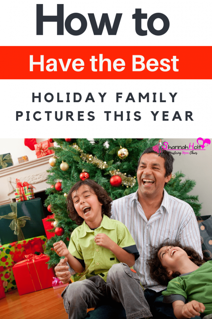 Father and two sons laughing while mom takes their family holiday picture in front of the Christmas tree. 