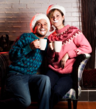 Woman and man with santa hats drinking hot cocoa with a whip cream mustache taking funny family holiday pictures