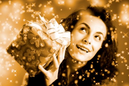 Woman posing for holiday photo while shaking a present. Image is using serpia photography. 