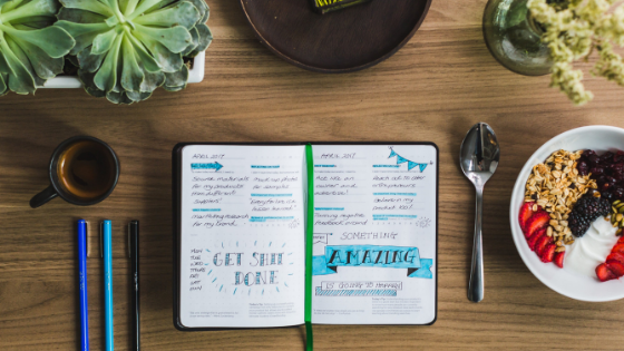 Fully written in journal sitting on the table surrounded by food. Journaling your food is a great way to help with weight loss. 