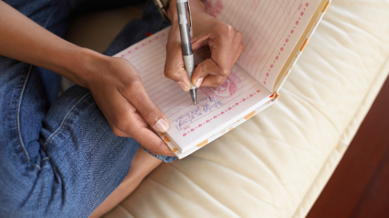 Woman sitting on bed journaling.